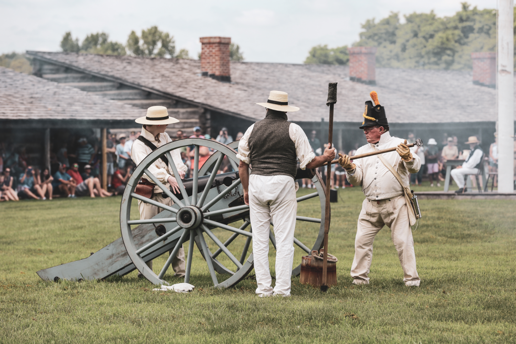 Men in period clothing load a cannon