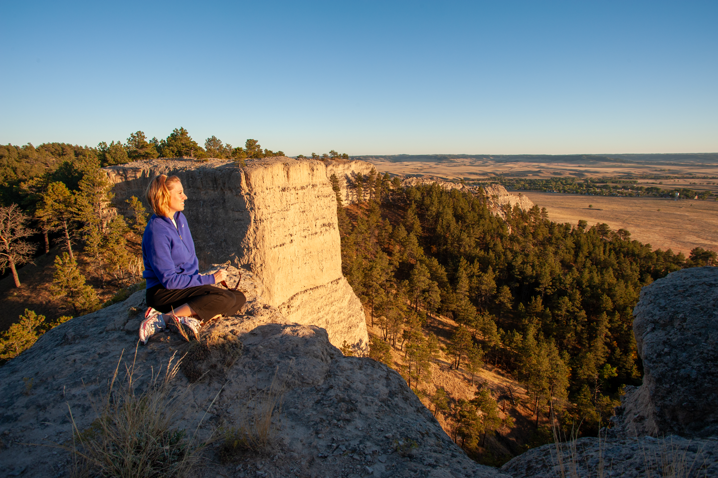 A woman sits on a butte