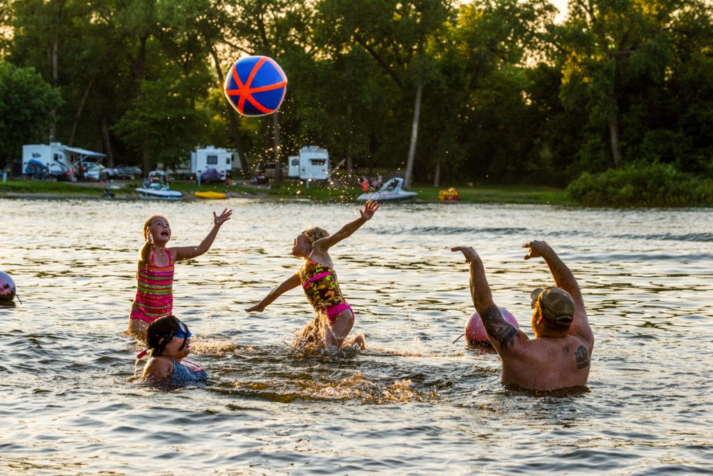 A family plays with a beach ball while swimming at a swim beach during summertime