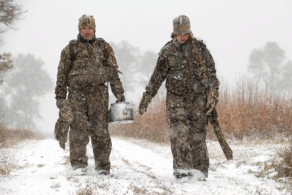 A dad and daughter in camouflage walking through the snow