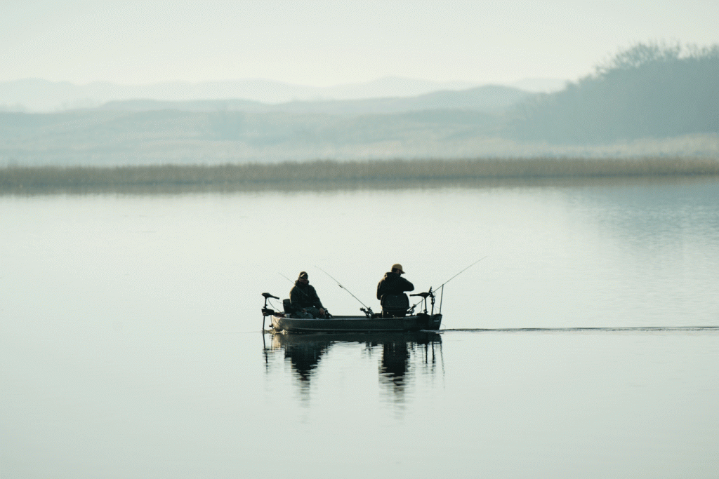 Two men fish from a boat in the center of a lake