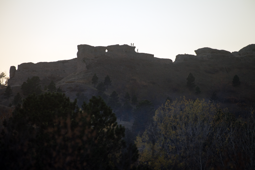 three hikers are silhouetted on a rocky outcrop