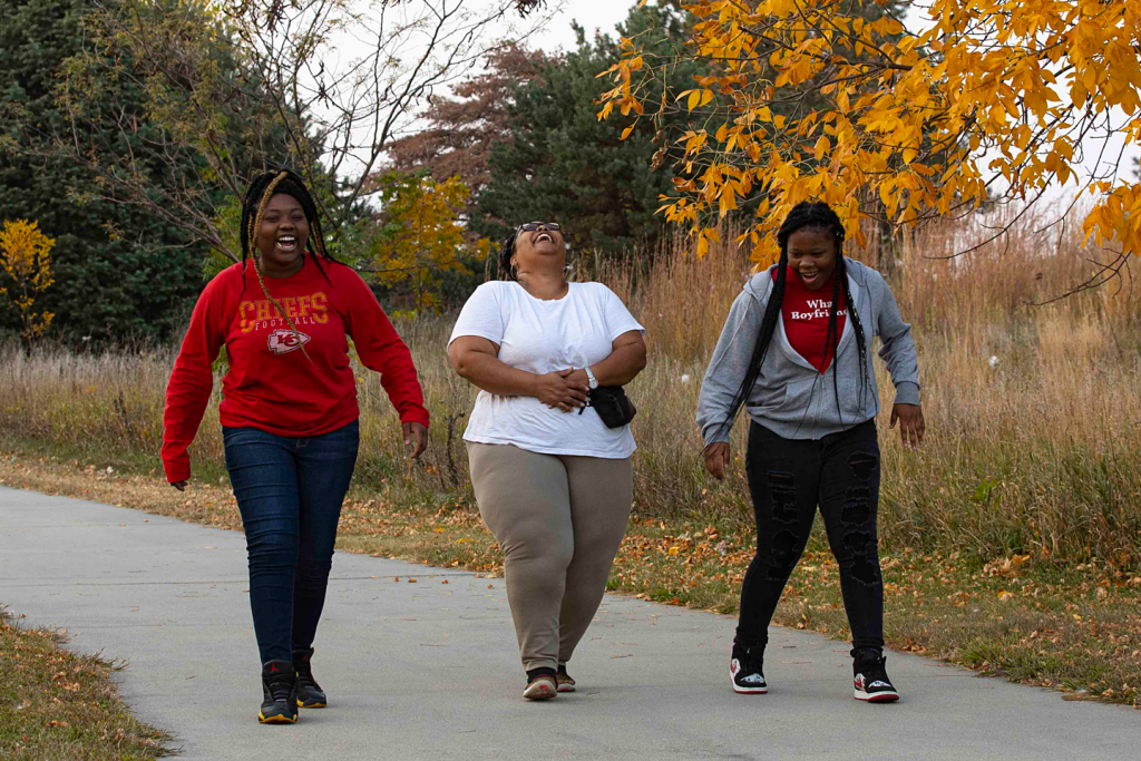 three women laugh as they walk a trail in the fall