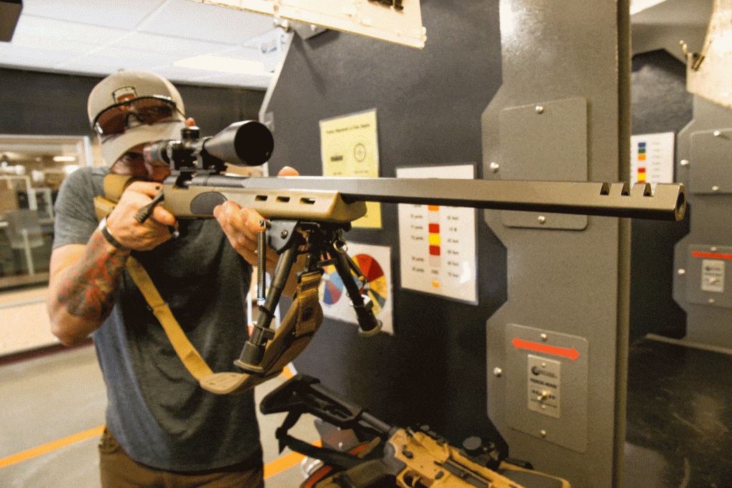 A man shoots a rifle at an indoor firearm range