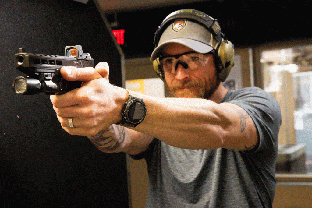 A man holds a handgun preparing to shoot at an indoor firearm range