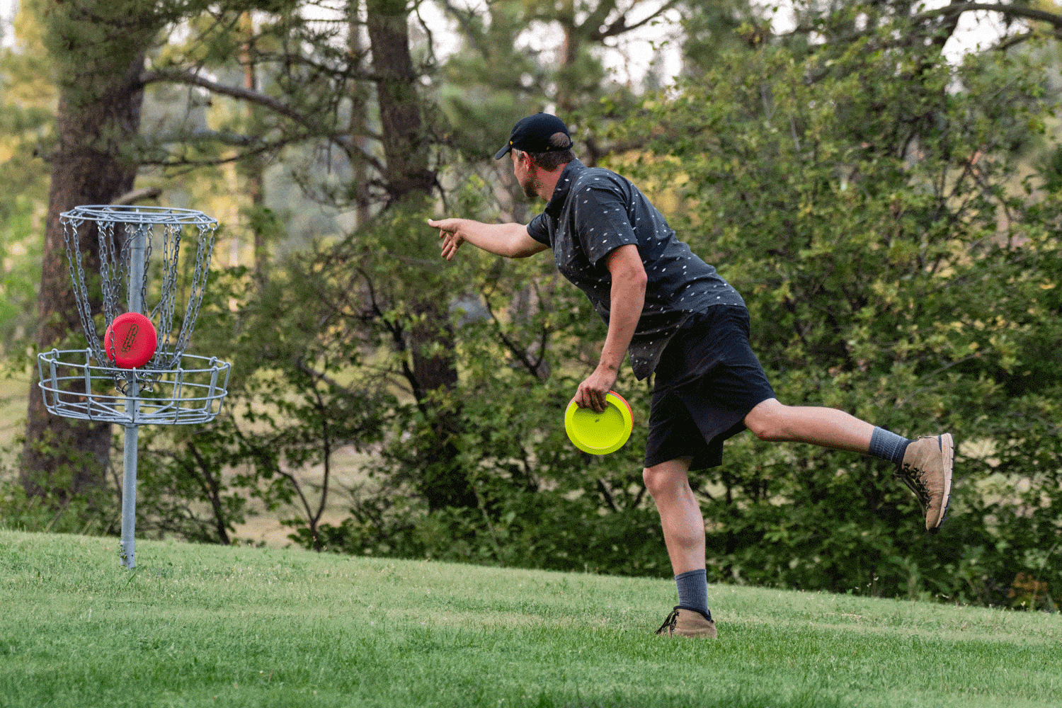 A man throws a disc on a disc golf course