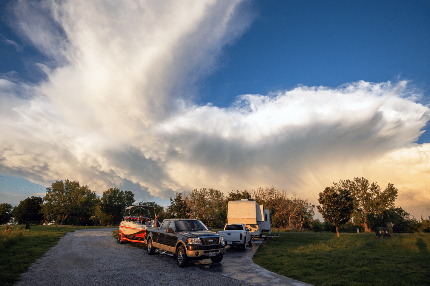 storm clouds rolling above a campground where a camper, truck and boat are parked