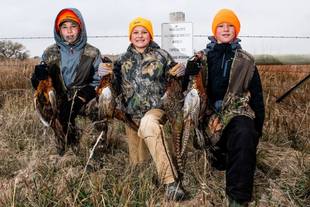 Three young boys pose with their harvested pheasants on youth season opener day at Bordeaux Creek Wildlife Management Area in Nebraska.
