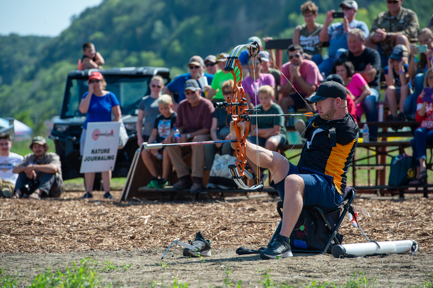 a man shoots a bow and arrow with his feet in front of a large crowd