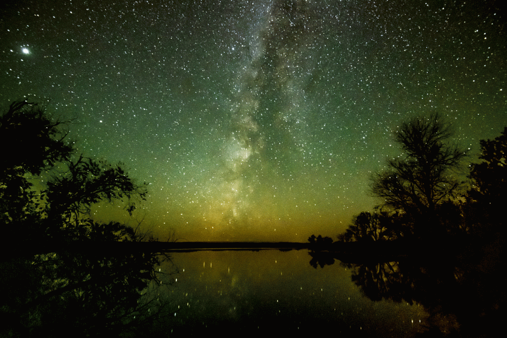 the milky way in a dark sky over a lake