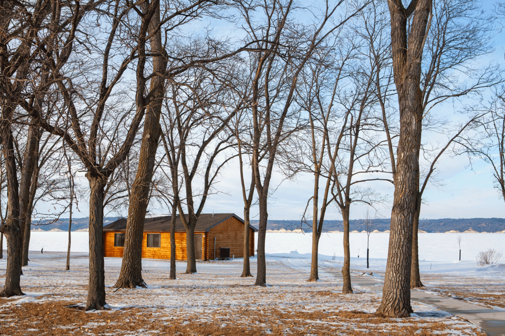 a cedar orange cabin in a snowy landscape next to a frozen lake