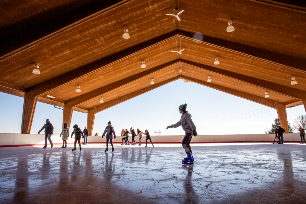 People ice skating at a covered ice skate rink during wintertime.