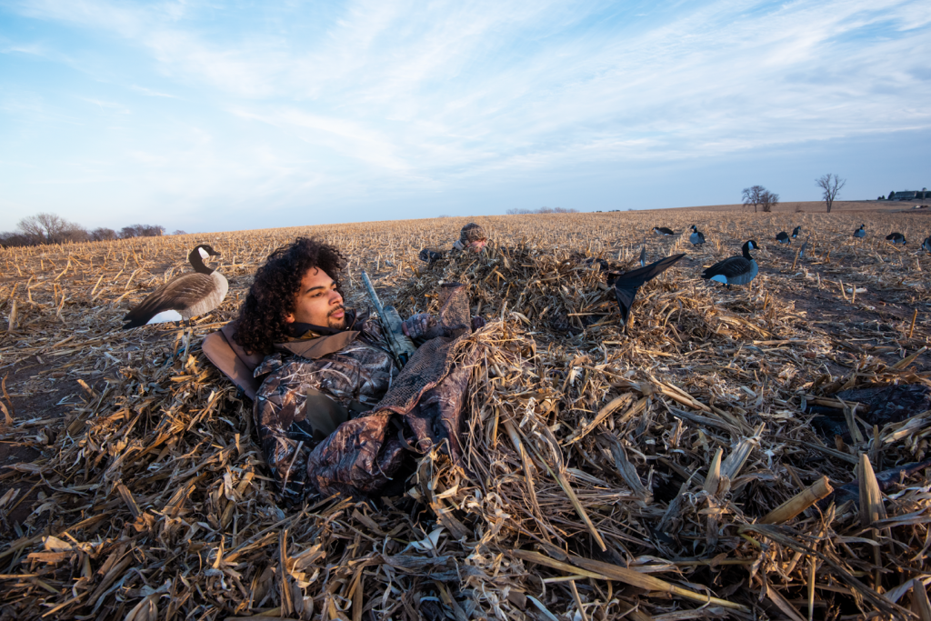 Two young men sit in goose blinds while hunting in Nebraska cornfields.