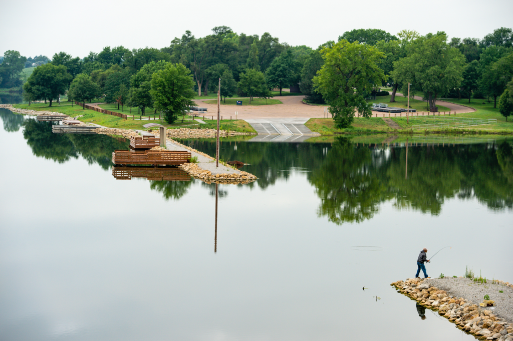 An angler fishes from a new breakwater at a lake.