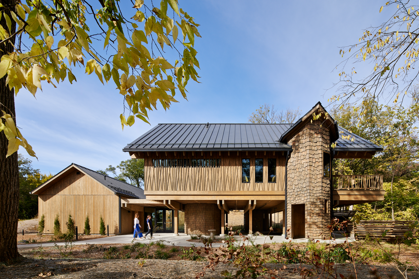 Two people walk outside of the new Treehouse building at Schramm Park State Recreation Area.