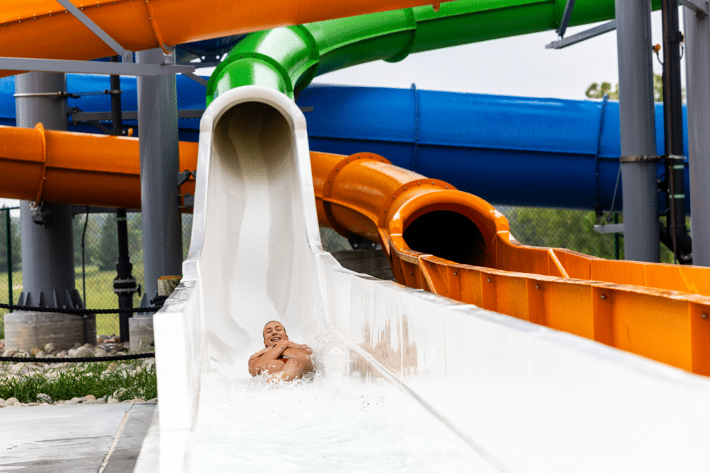 A young woman sliding down the end of a large waterslide.