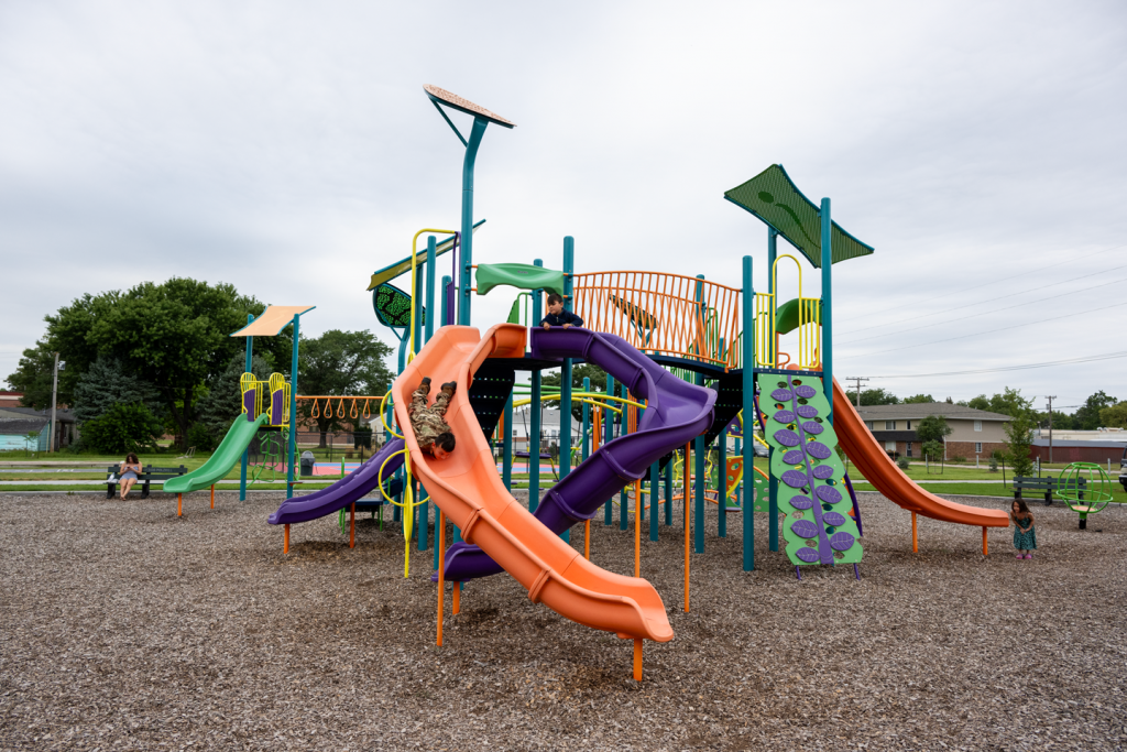 a kid goes head first down an orange slide